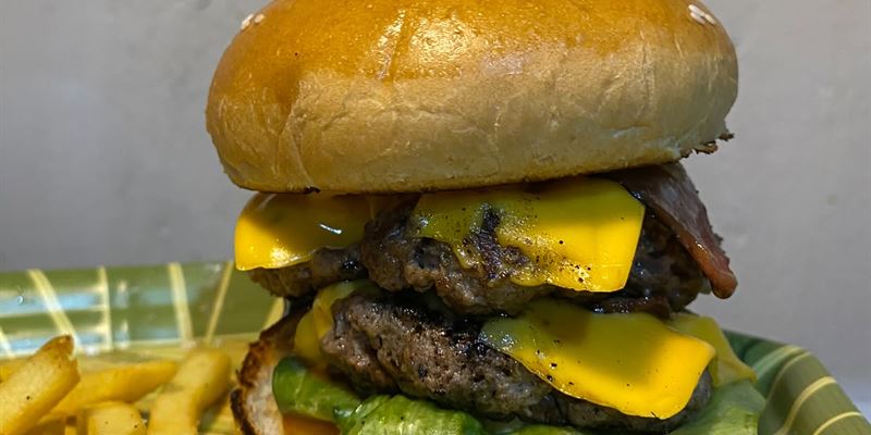 Hamburguesa de doble carne con queso cheddar, lechuga y tomate, acompañada de papas a la francesa