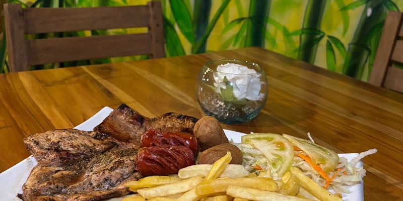 Plato de parrillada con pollo, chorizo, papas a la francesa y ensalada, servido en una mesa del local