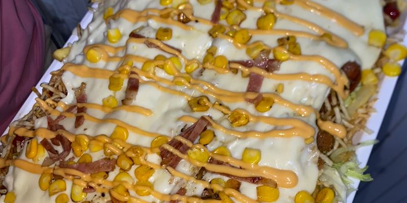Picatón: bandeja de papas bañadas en queso fundido con maíz tierno, tocineta y salsa de la casa